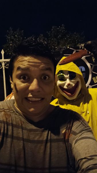 Anfitrión disfrazado se toma una selfie con personaje de impermeable amarillo en Halloween