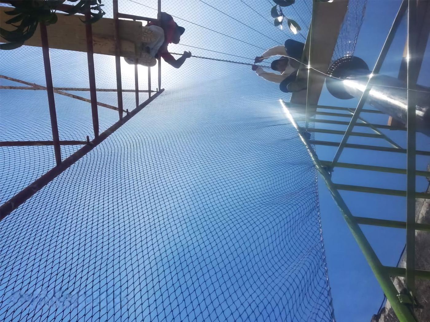 Trabajadores instalando una red en altura sobre una estructura metálica