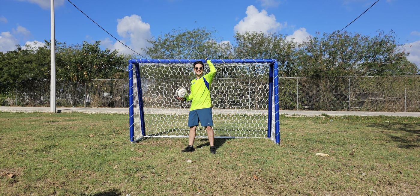 Portería de fútbol forrada en azul con red hexagonal blanca en un parque