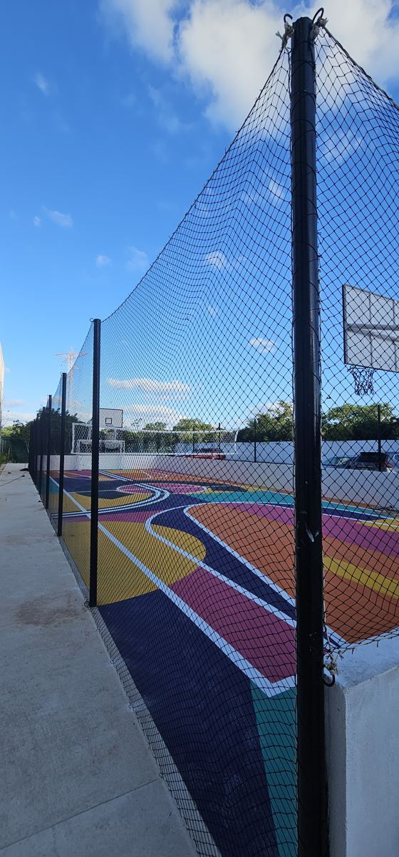 Red perimetral negra con postes en una cancha multiusos de básquetbol
